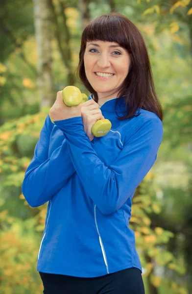 Vrouw tijdens fitnesstraining met halters in het park. Ontspanning op de frisse lucht — Stockfoto