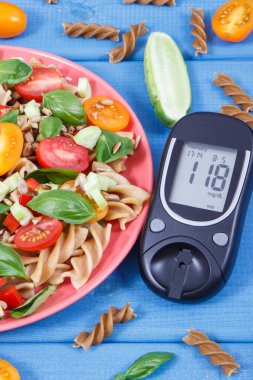 Şekerli glukometre, kepekli makarna ve sebzeli salata. Vitamin ve mineral içeren sağlıklı bir yemek.