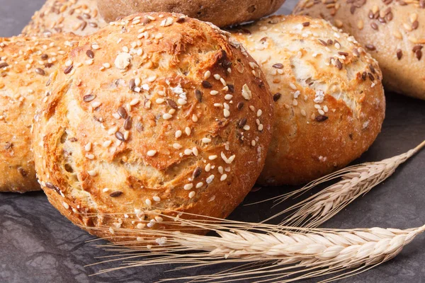 Fresh baked rolls with seeds and ears of rye or wheat grain — Stock Photo, Image