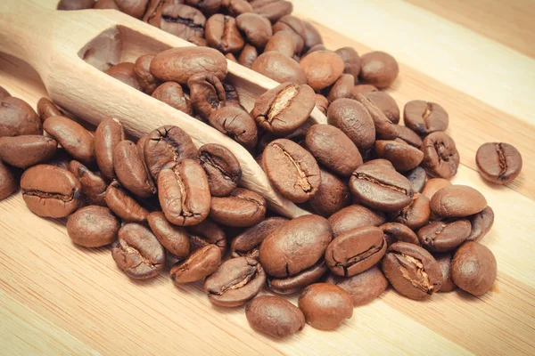 Haufen Gerösteter Kaffeekörner Mit Löffel Auf Holzbrett — Stockfoto