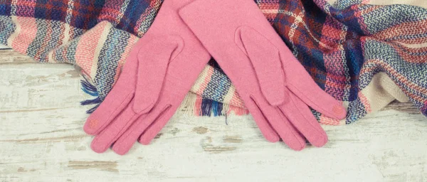 Woolen womanly pink gloves and colorful shawl or scarf, warm clothing for autumn or winter concept