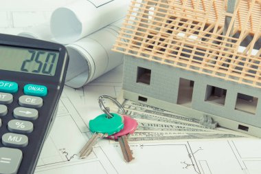 İnşaat, ev anahtarları, hesap makinesi ve elektrik çizimlerini ve diyagramlarını projesi, ev maliyet bina kavramı için para birimlerinin dolar altında küçük ev