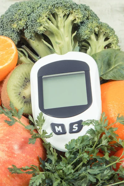 Glucometer for measuring sugar level and ripe natural fruits and vegetables. Concept of diabetes, healthy lifestyles and nutrition