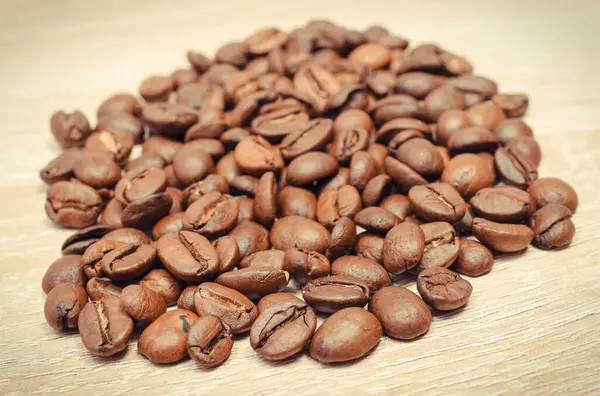 木の板の上で焙煎したコーヒー粒のヒープ — ストック写真