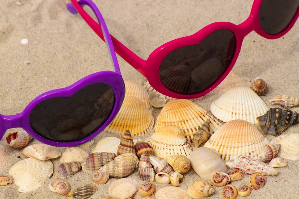 沙滩上躺着一堆堆心形的贝壳和五颜六色的太阳镜 — 图库照片