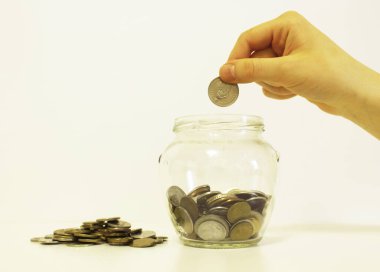 El, biriktirmek için parayı cam kavanoza atıyor.