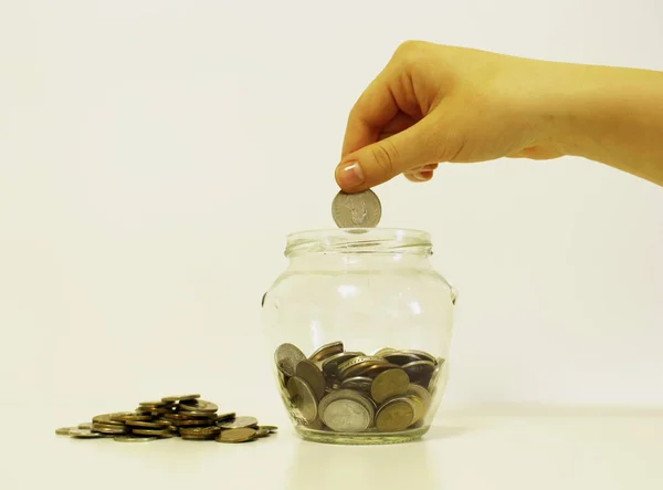 hand drops money into a glass jar for a savings