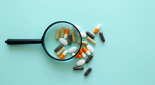 İnceleme altındaki haplar. İlaç, ilaç, vitamin, eczane, büyüteç, konsept