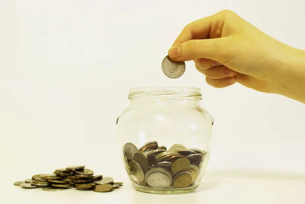 hand drops money into a glass jar for a savings