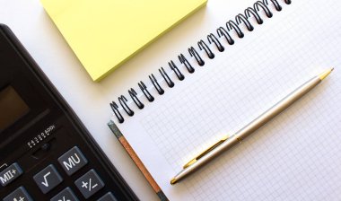 Beyaz arkaplanda hesap makinesi kalem ve defter
