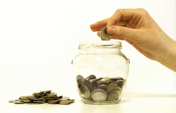 Рука роняет деньги. стеклянная банка для экономии
