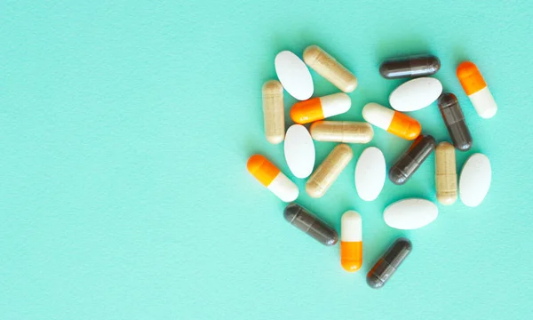 A handful of colored pills spilled out of the can on a blue background. Medical concept.