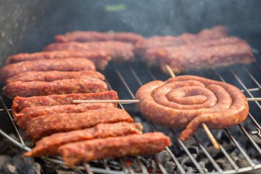 Sosisler ve mici veya mititei adı verilen geleneksel Romen sosisleri (et ve baharat karışımından silindirik şeklinde ızgara et rulolarından oluşan yemek) dumanlı barbekü üzerine