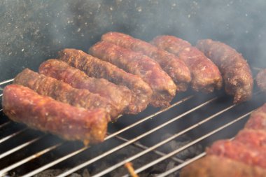 Sosisler ve mici veya mititei adı verilen geleneksel Romen sosisleri (et ve baharat karışımından silindirik şeklinde ızgara et rulolarından oluşan yemek) dumanlı barbekü üzerine