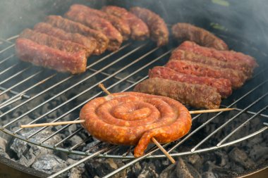Sosisler ve mici veya mititei adı verilen geleneksel Romen sosisleri (et ve baharat karışımından silindirik şeklinde ızgara et rulolarından oluşan yemek) dumanlı barbekü üzerine
