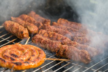 Sosisler ve mici veya mititei adı verilen geleneksel Romen sosisleri (et ve baharat karışımından silindirik şeklinde ızgara et rulolarından oluşan yemek) dumanlı barbekü üzerine