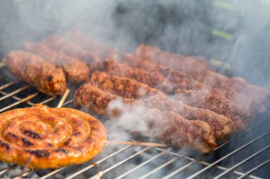 Sosisler ve mici veya mititei adı verilen geleneksel Romen sosisleri (et ve baharat karışımından silindirik şeklinde ızgara et rulolarından oluşan yemek) dumanlı barbekü üzerine