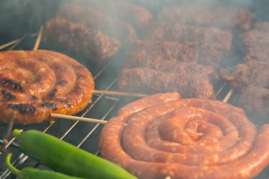 Sosisler ve mici veya mititei adı verilen geleneksel Romen sosisleri (et ve baharat karışımından silindirik şeklinde ızgara et rulolarından oluşan yemek) dumanlı barbekü üzerine