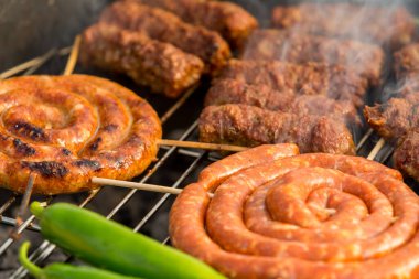 Sosisler ve mici veya mititei adı verilen geleneksel Romen sosisleri (et ve baharat karışımından silindirik şeklinde ızgara et rulolarından oluşan yemek) dumanlı barbekü üzerine