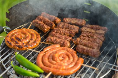 Sosisler ve mici veya mititei adı verilen geleneksel Romen sosisleri (et ve baharat karışımından silindirik şeklinde ızgara et rulolarından oluşan yemek) dumanlı barbekü üzerine