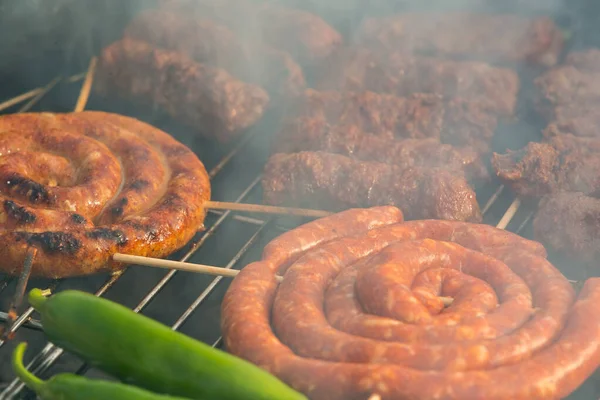 Sosisler ve mici veya mititei adı verilen geleneksel Romen sosisleri (et ve baharat karışımından silindirik şeklinde ızgara et rulolarından oluşan yemek) dumanlı barbekü üzerine