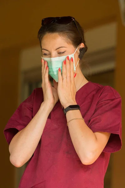 A veterinarian doctor covers her face with a medical mask during a pet grooming session at home