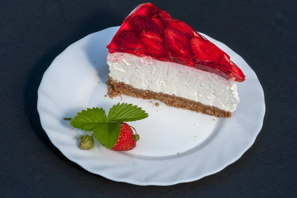 Strawberry cheesecake with fresh strawberries perfectly arranged on a white plate