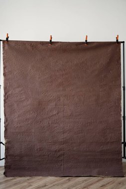 Kahverengi desenli arka plan metal raflarda asılı, portre çekimi için buruşuk arka plan beyaz duvarlı ve ahşap zeminli bir fotoğraf stüdyosunda.,
