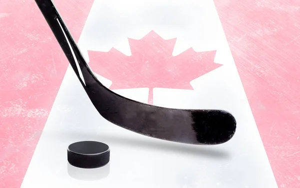 Vara e pato de hóquei com bandeira canadense no gelo — Fotografia de Stock