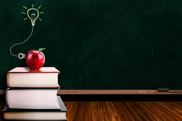 Bildungsidee mit Apfel auf Buch und Glühbirne auf Tafel — Stockfoto