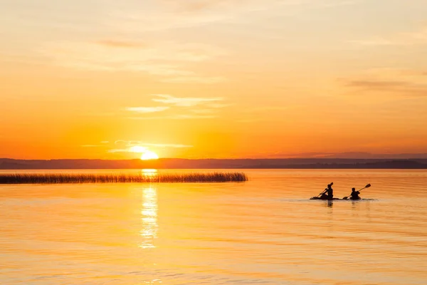 Силуэт двух каноистов на озере во время заката — стоковое фото