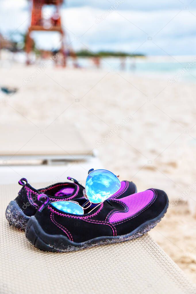 Pair of Sunglasses and Water Shoes on Beach With Copy Space