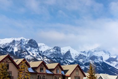 Rows of houses in the Canadian Rockies of Canmore, Alberta, with spectacular view of Rundle Mountain in the background. clipart