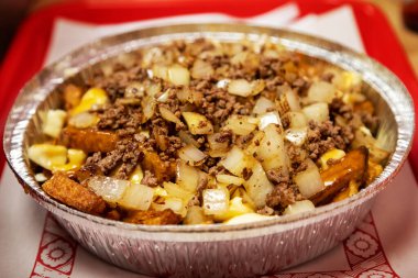 Elle kesilmiş patates kızartması ve peynirli poutine olarak bilinen meşhur Kanada mutfağı üzerine soğan, kıyma ve kahverengi sos. Bu yemek Kanada 'nın Quebec eyaletinden geliyor..