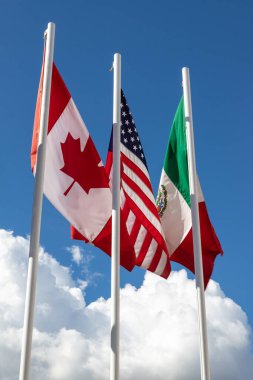 ABD, Meksika ve Kanada 'dan oluşan 3 USMCA ülkesinin bayrakları gökyüzüne karşı bayrak direğinde, ABD' de USMCA olarak bilinen yeni NAFTA anlaşması konsepti, Kanada 'da CUSMA veya Meksika' da T-MEC.