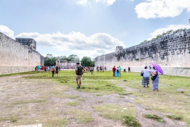 Chichen Itza, Meksika - 23 Aralık 2019: Turistler antik Pok-a-Tok veya Juego de Pelota oyununun oynandığı Meksika 'nın Yucatan Yarımadası' ndaki Chichen Itza 'daki Büyük Ballcourt arkeolojik sahasını ziyaret ettiler..