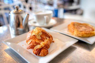 Kahvaltı bademli kruvasan puf böreği ve bir fincan latte kahve..