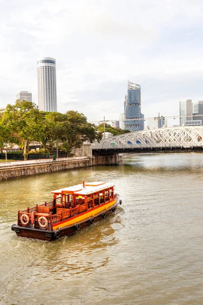 Boat on the Singapore River at Boat Quay moving toward Anderson Bridge with downtown skyline in the background. Opened in 1910, the historic truss bridge was named after Sir John Anderson, the Governor of the Straits Settlements.