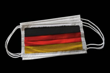 Alman bayrağı basılmış birden fazla cerrahi maske. Siyah arka planda izole edilmiş. Covid-19 Coronavirus salgınıyla savaşma çabalarında yüz maskesi kullanımı kavramı.