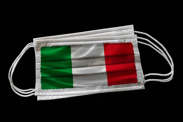 イタリアの国旗が印刷された複数の外科用フェイスマスク 黒の背景に隔離されてる Covid 19コロナウイルスパンデミックと戦うためのイタリアの努力における顔マスク使用の概念 — ストック写真