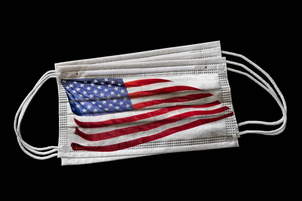 Multiple surgical face masks with flying US American Flag printed. Isolated on black background. Concept of face mask usage in United State's effort to combat Covid-19 coronavirus pandemic.