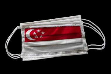 Singapur bayrağı basılmış cerrahi yüz maskeleri. Siyah arka planda izole edilmiş. Covid-19 Coronavirus salgınıyla savaşmak için Singapur 'da yüz maskesi kullanımı kavramı.