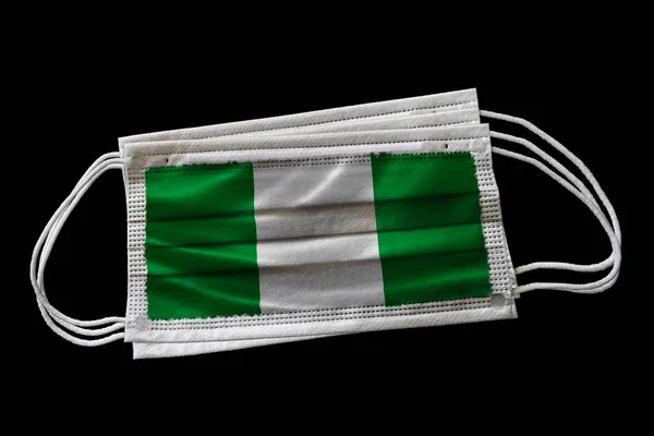ナイジェリアの国旗が印刷された外科用フェイスマスク 黒の背景に隔離されてる ナイジェリアにおける顔マスクの使用の概念Covid 19コロナウイルスのパンデミックと戦うための努力 — ストック写真