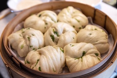 Çin Dim Sum buğulanmış soğanlı soğanlı çörekler bambu buharlı tencerede servis ediliyor. Dim sum, Çin 'in güneyinde ve Hong Kong' da Çin mutfağına ait eşsiz bir mutfak sanatı türüdür..