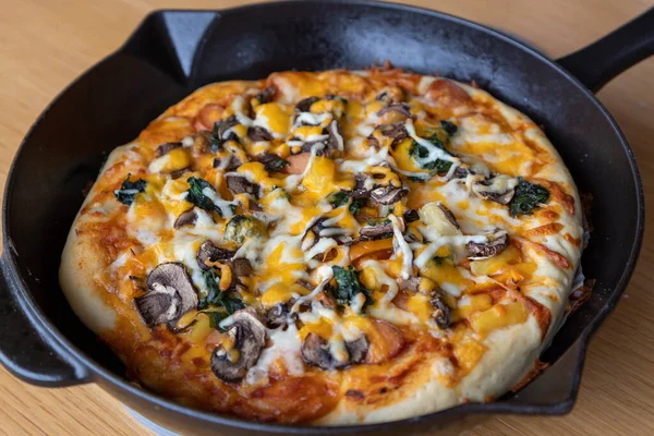 Closeup of homemade vegetarian pan pizza with mushroom, spinach; onion; cheese; bell pepper; and variety of vegetable toppings and aromatic herbs