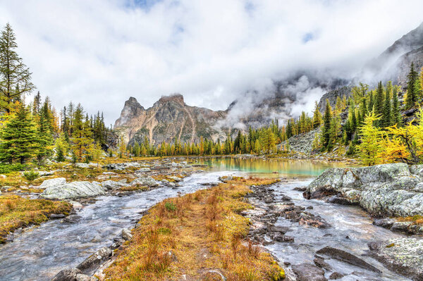 Осенняя сцена на озере О 'Хара в Канадских Скалистых горах национального парка Йохо с лиственницами, золотистыми на Мавританских озерах и густым туманом на горе Юнесс
.