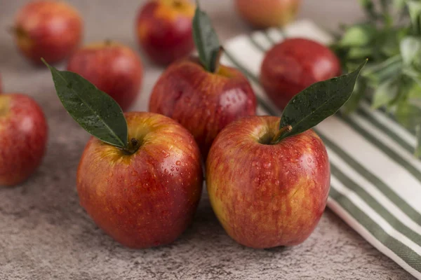 Красные яблоки с листьями на сером фоне — стоковое фото
