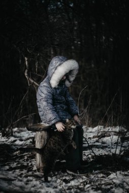 Kışın ormanda kedisi olan bir kız.