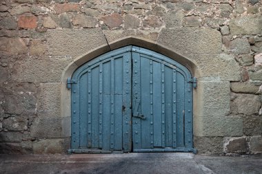Taş duvarda kemer olan eski, tahta bir kapı.