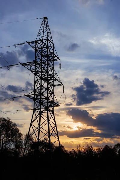 Cut wires on a power line support with a sunset background